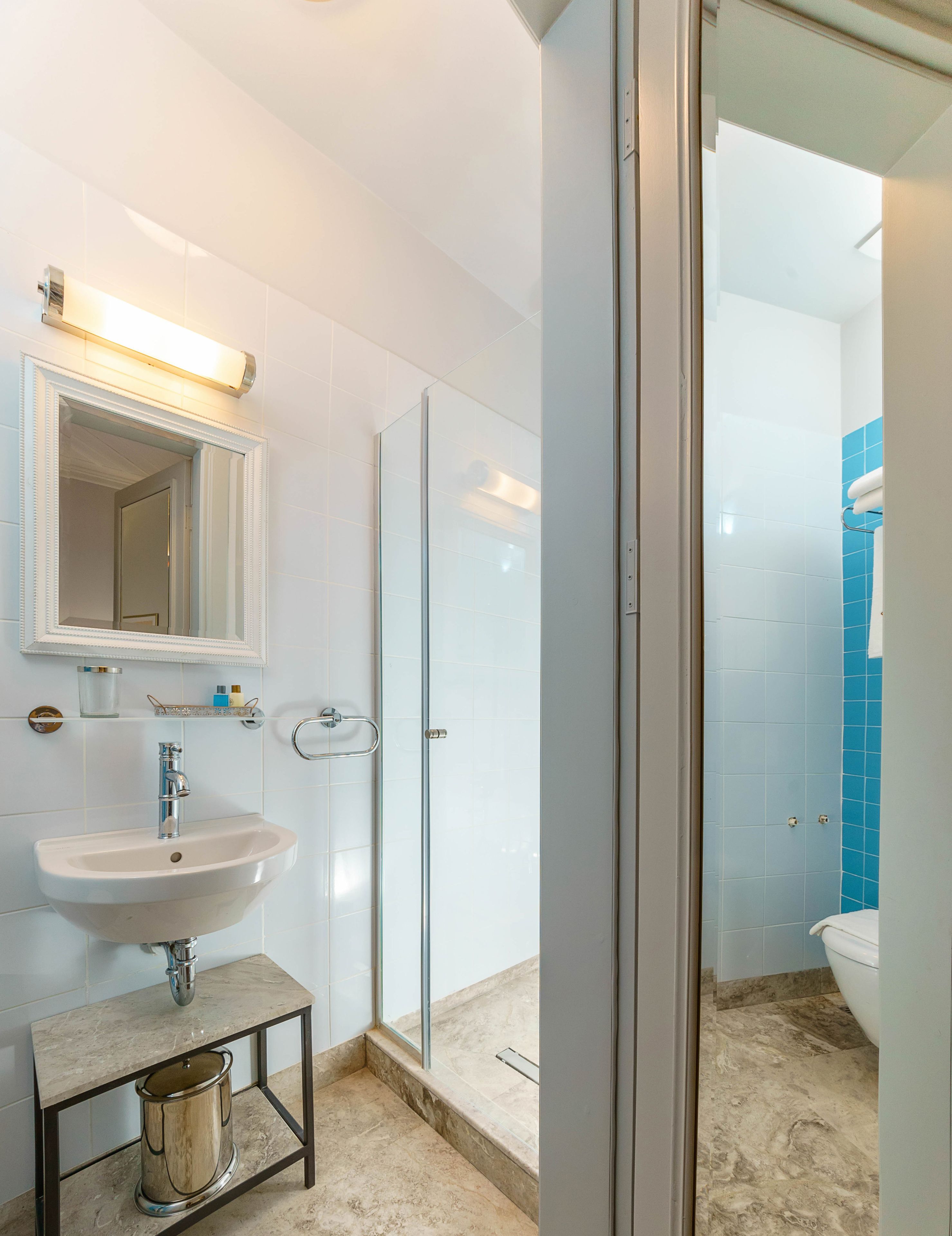 Une salle de bain moderne avec une douche à parois de verre, un lavabo avec un miroir au-dessus et des toilettes recouvertes de carreaux bleus.
