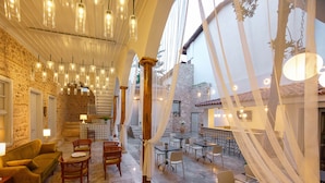 A spacious indoor area with stone walls, multiple tables and chairs, and hanging pendant lights. - Delight Deluxe Hotel (Antalya)