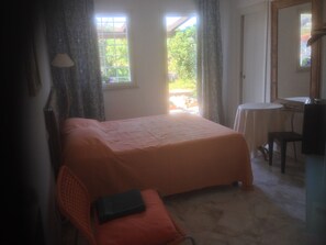 A bedroom with a bed, a chair, a small table, and a mirror. - Le Stanze sul Mare (Carini)