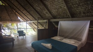 Una habitación con cama, una silla y suelo de madera.