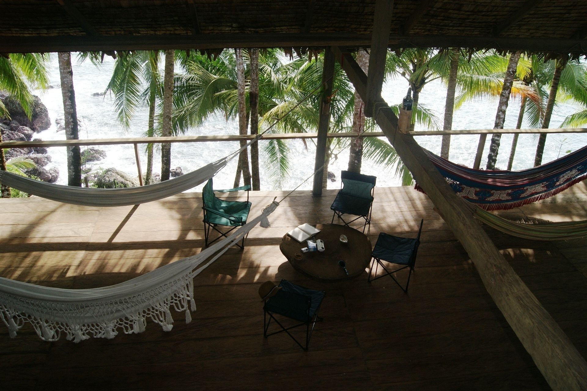 A wooden deck with a hammock, two chairs, and a table.