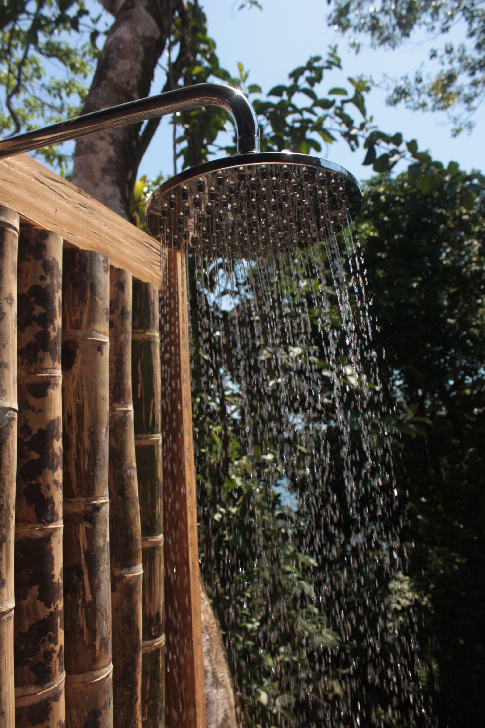 Un cabezal de ducha con agua cayendo sobre una estructura de bambú.