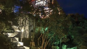 A modern house with a unique roof design, surrounded by lush greenery and a well-lit staircase. - Villas Del Sol Resort (Koh Tao)
