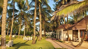 A resort with palm trees, outdoor seating, and a building with large windows. - Silver Palm Spa and Resort (Kilifi)