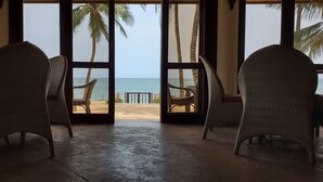 A room with wicker chairs facing a beach view through large windows. - Silver Palm Spa and Resort (Kilifi)