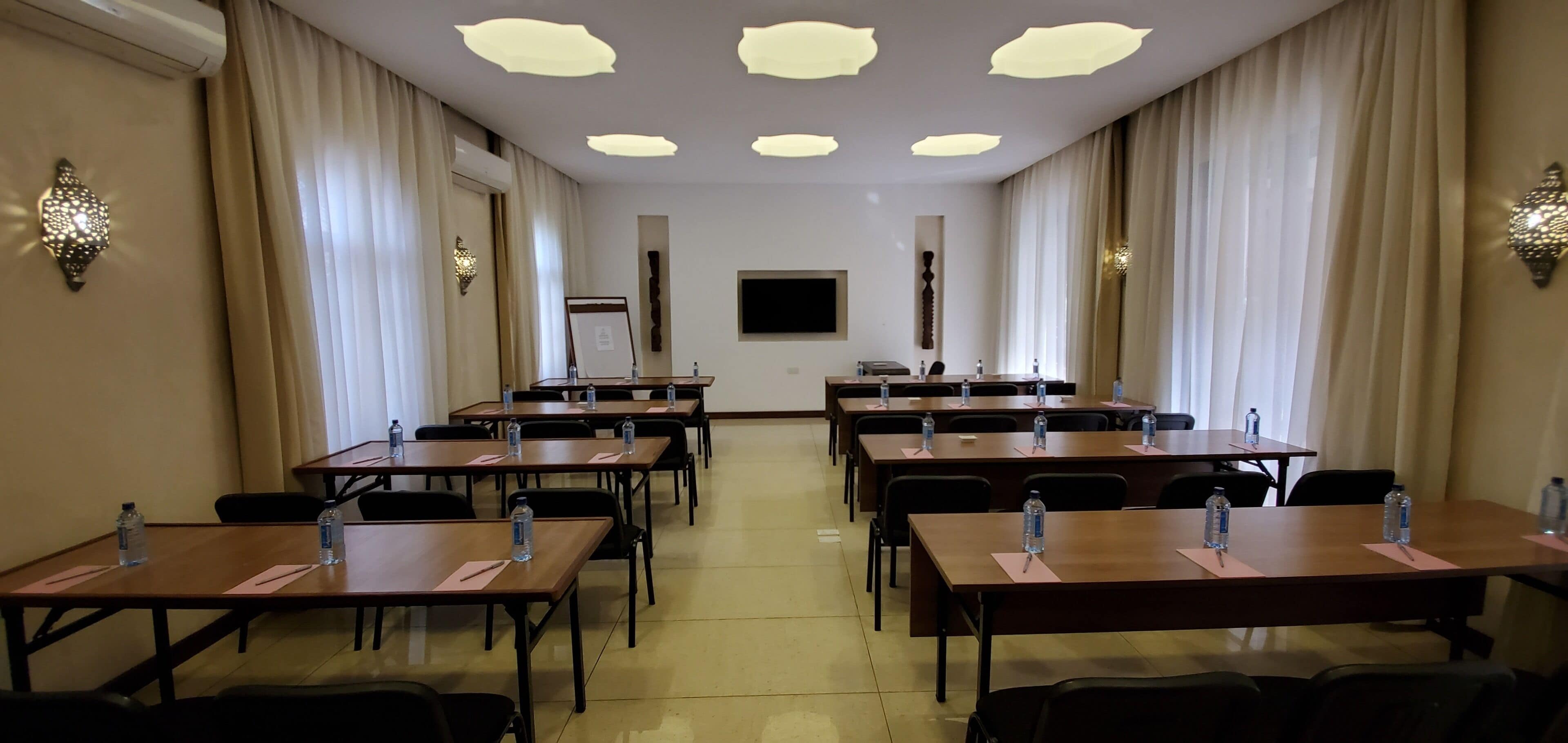 A conference room with multiple tables, chairs, and water bottles.