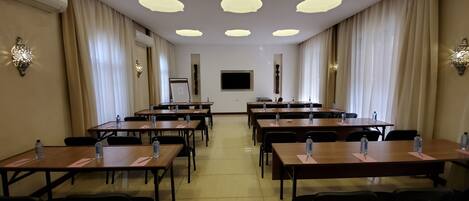 A conference room with multiple tables, chairs, and water bottles.