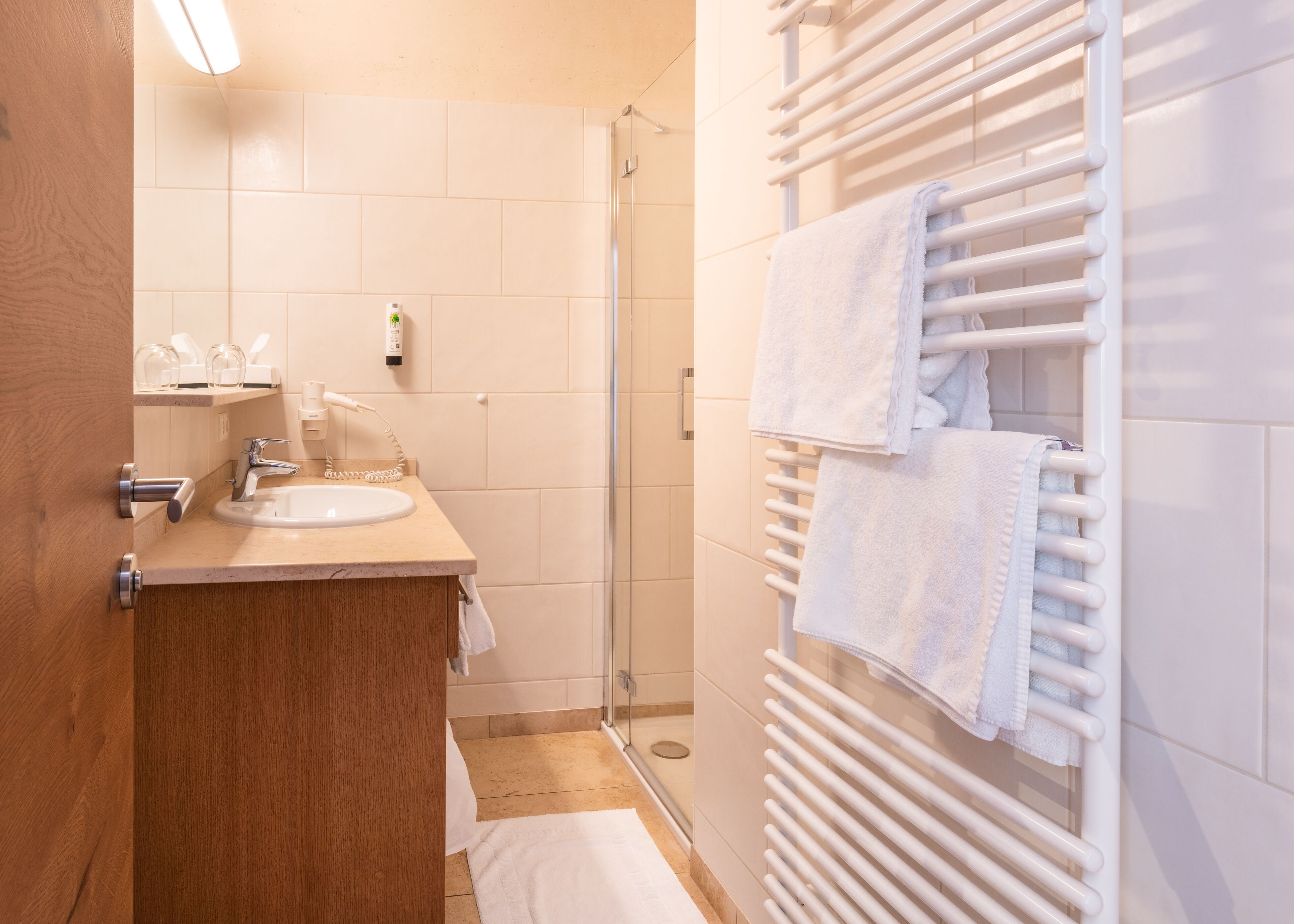 A modern bathroom with a sink, mirror, and towel rack.