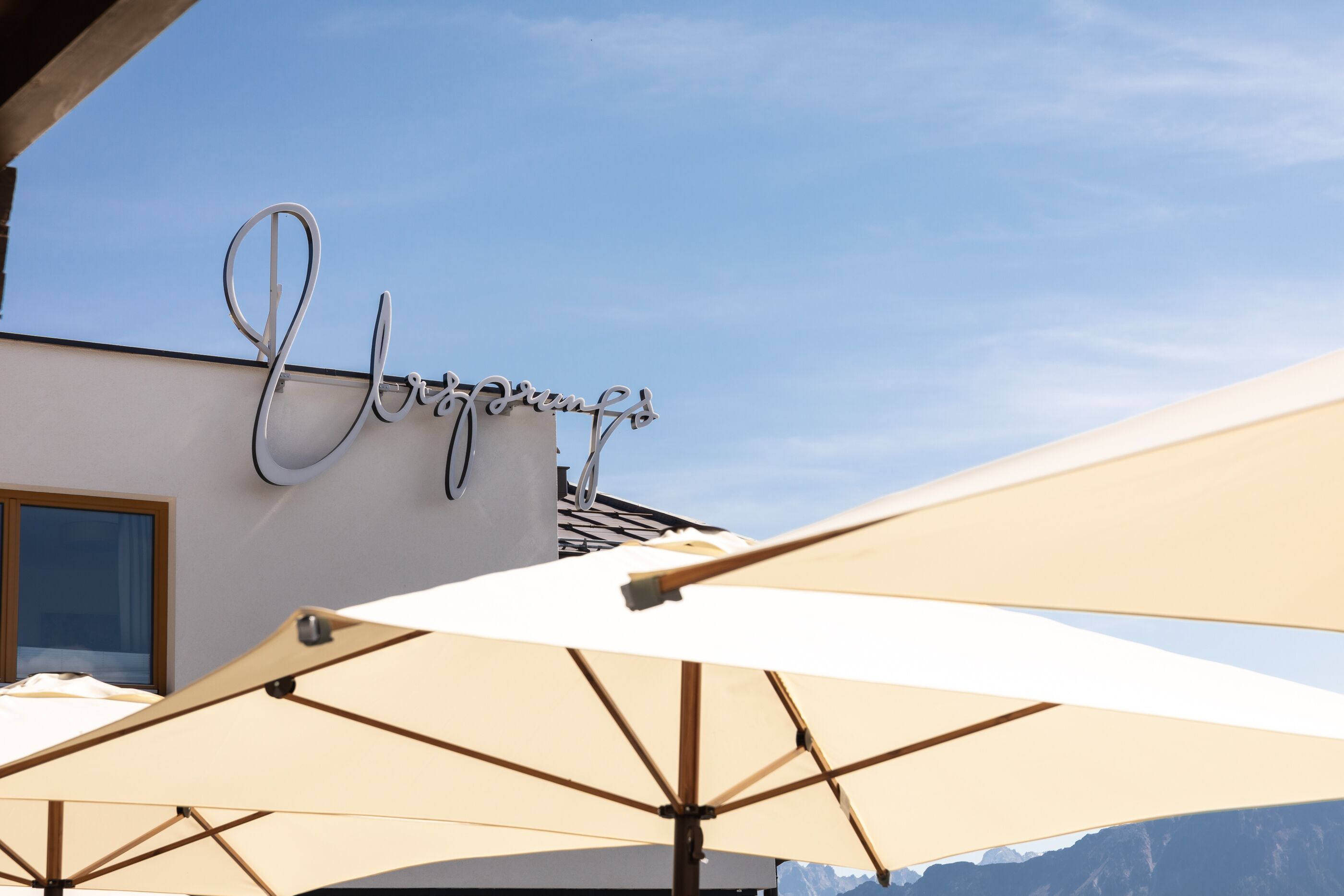 Een hotel met parasols en een bord met sierlijk schrift.