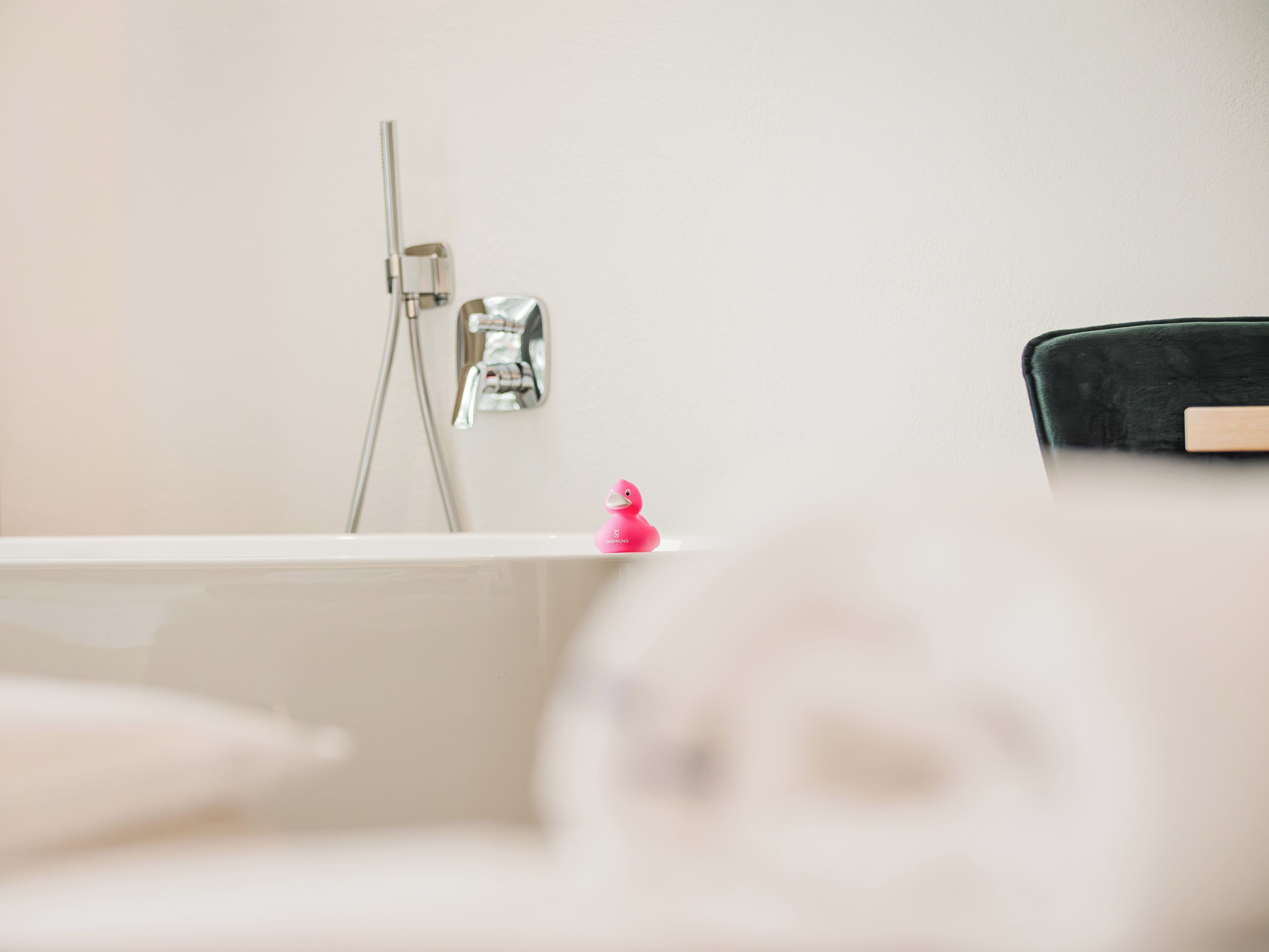 Ein Badezimmer mit Badewanne, Dusche und einem kleinen, rosa Gummibadenten.