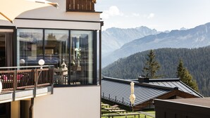 Un bâtiment moderne doté de grandes fenêtres, d’un balcon et offrant une vue sur un paysage montagneux.
