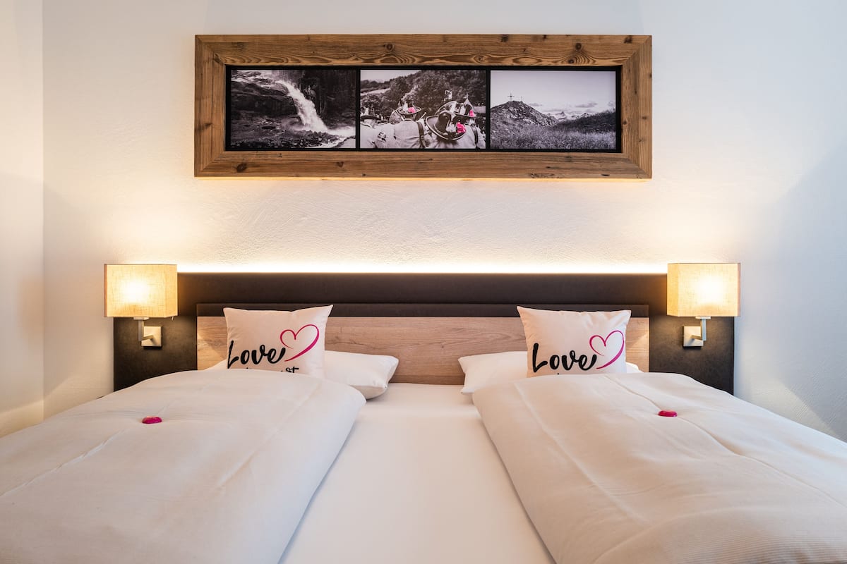 Una cama doble con dos lámparas de noche, un cabecero de madera y dos almohadas con la palabra 'love'.