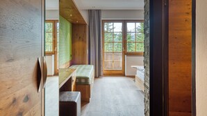 Una habitación con un banco de madera, una mesita y una ventana que da a vistas de vegetación.