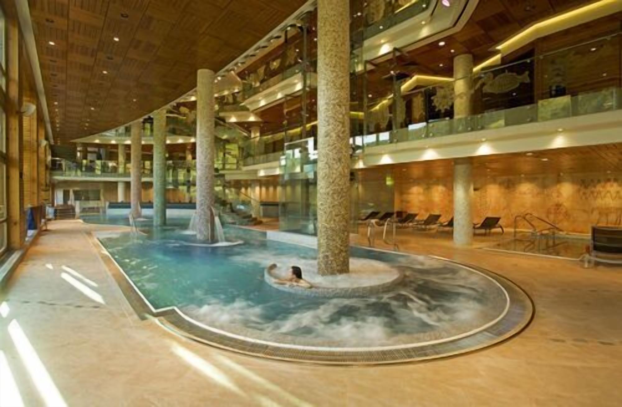 A spacious indoor pool area with a central water feature and multiple levels of balconies.