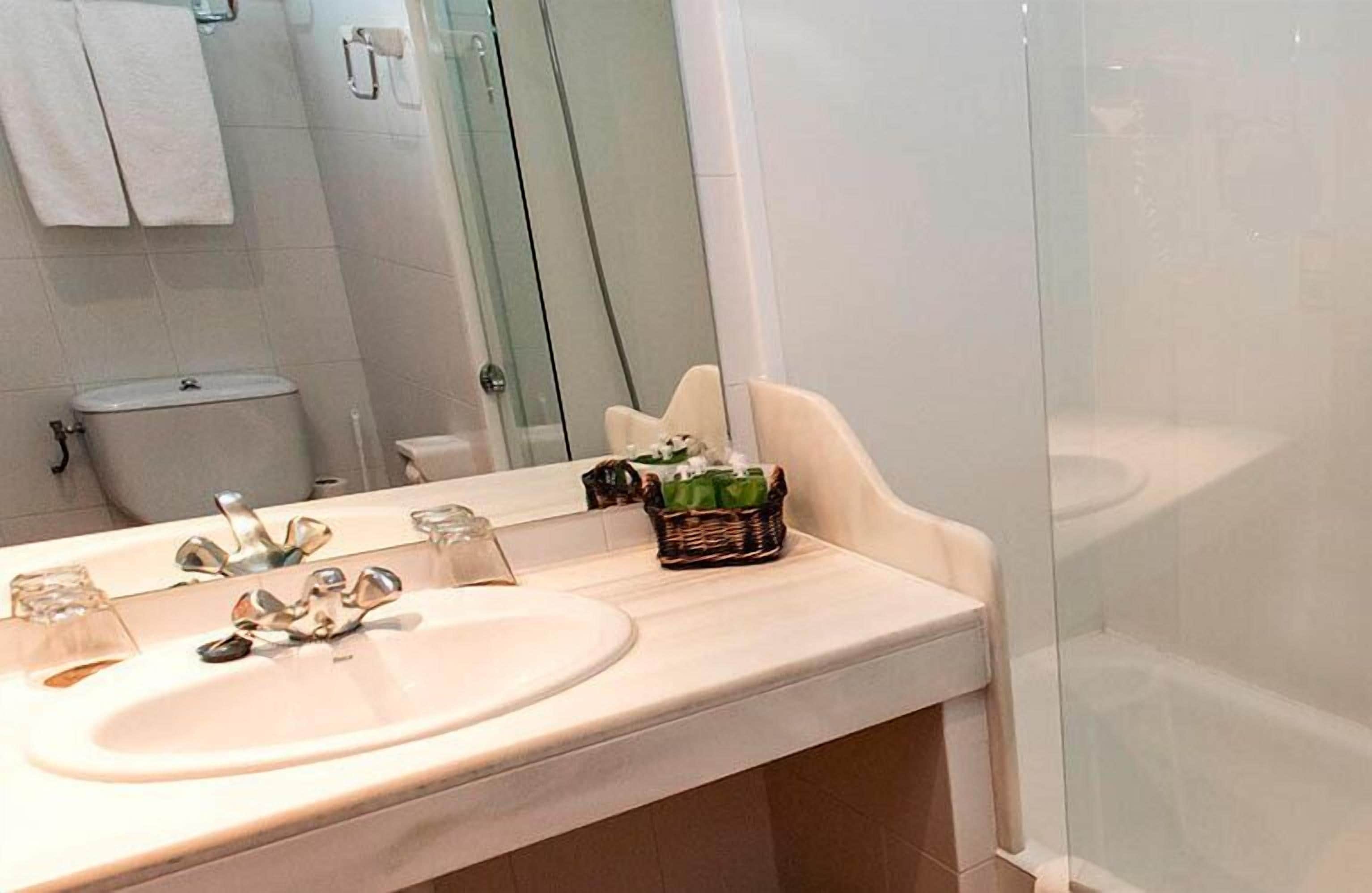 A bathroom with a sink, mirror, and glass shower enclosure.