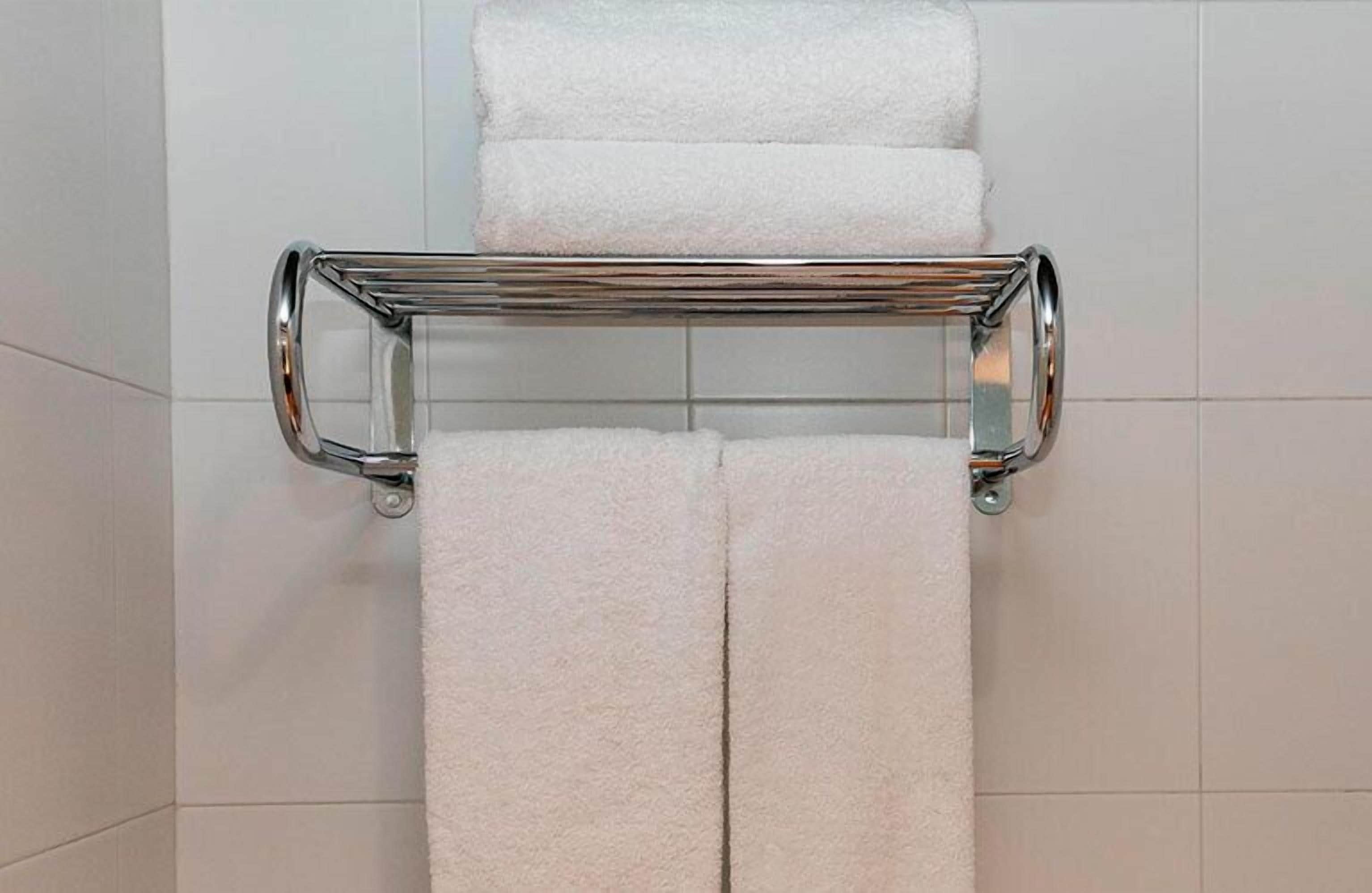 Ein Badezimmer mit einem chromfarbenen Handtuchhalter, der zwei weiße Handtücher trägt.