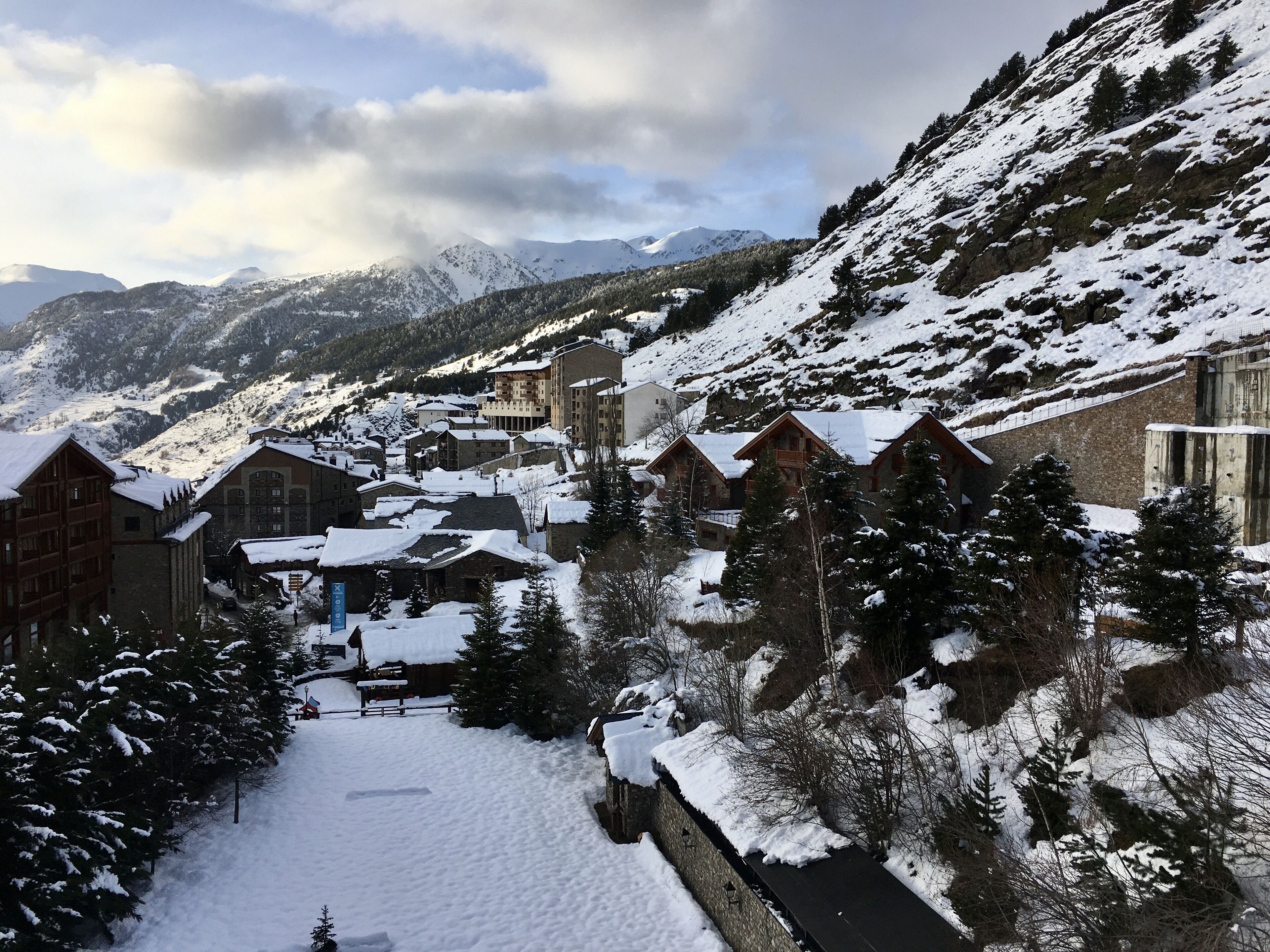 A snow-covered mountain town with traditional wooden buildings and a stone wall.