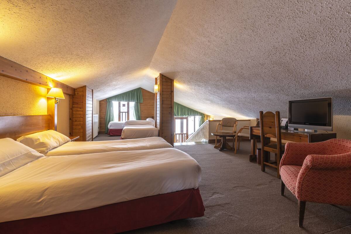 A hotel room with two beds, a TV, a desk, and a chair.