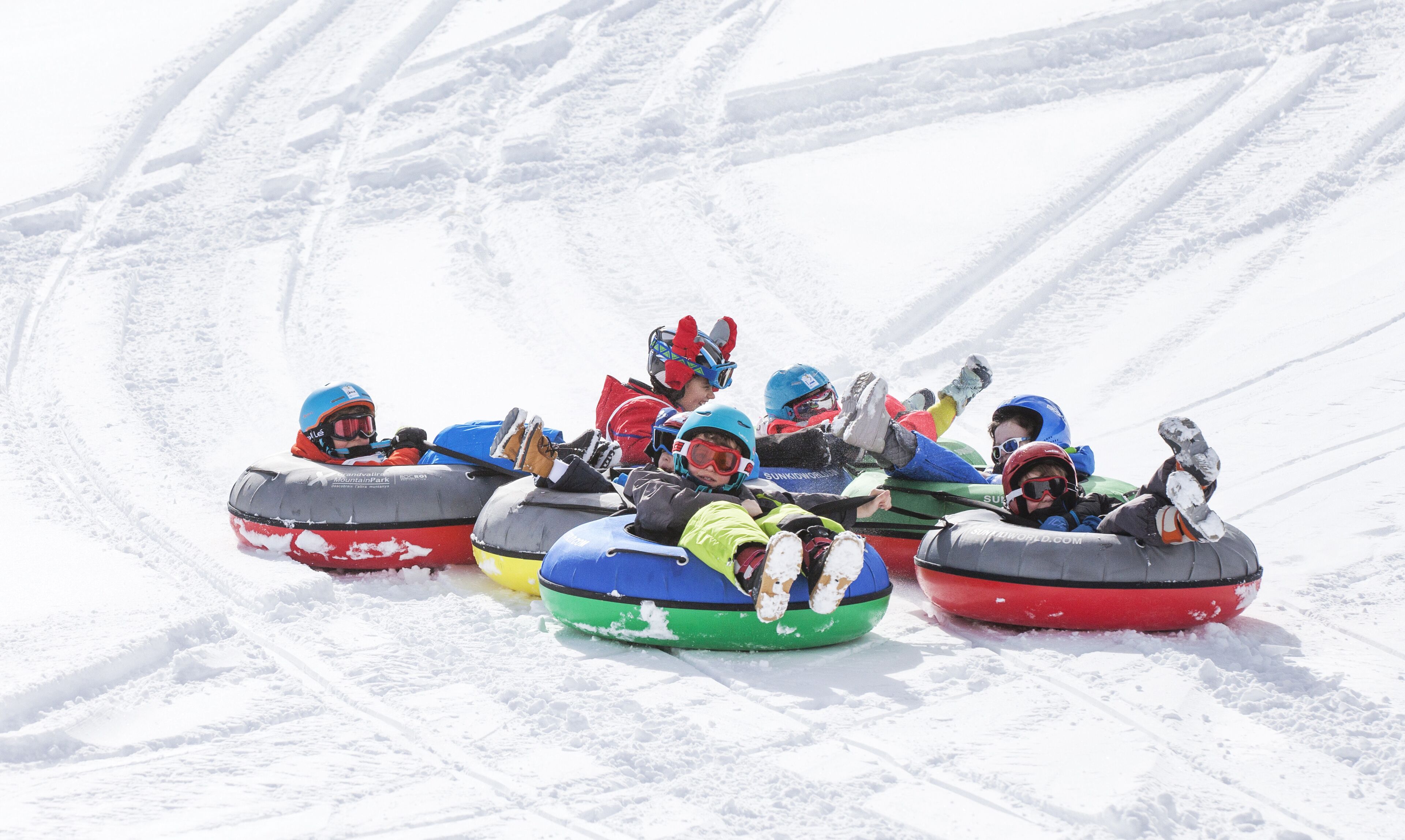 People in colorful snow tubes on a snowy slope.