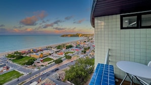 Uma varanda com vista para uma cidade costeira, uma área de refeições e um edifício com fachada em azulejos.