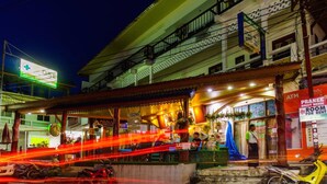 A building with a pharmacy sign, a guest house for rent, and a visible ATM. - Pranee Guesthouse (Koh Tao)