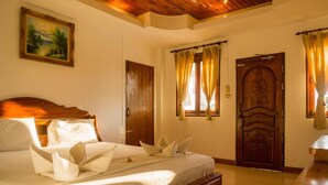 A hotel room with a wooden bed, a painting on the wall, a wooden door, and curtains. - Pranee Guesthouse (Koh Tao)