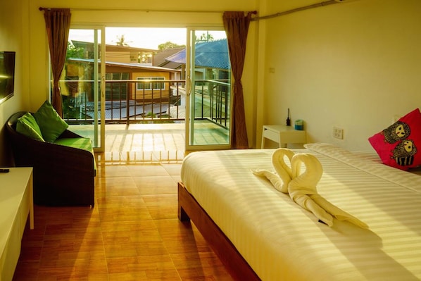 A hotel room with a bed, a sofa, a TV, and a balcony with a view of buildings.