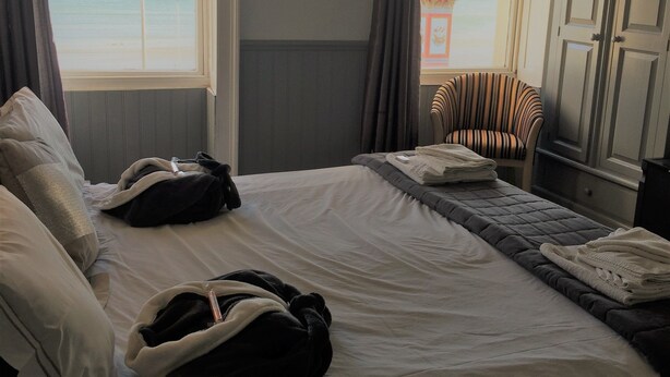 A hotel room with a bed, a chair, and a view of the sea. - The Leam Hotel (Weymouth)