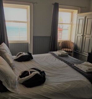 Een hotelkamer met een bed, een stoel en uitzicht op zee.