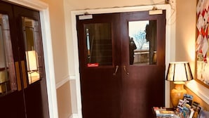 A reception area with a sign pointing to the reception, a dark wooden door, and a magazine rack with brochures. - The Leam Hotel (Weymouth)