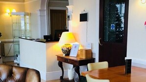 A dining area with a wooden table and chairs, a leather armchair, and a red rug. - The Leam Hotel (Weymouth)