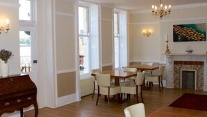 A spacious room with a fireplace, dining area, and large windows. - The Leam Hotel (Weymouth)