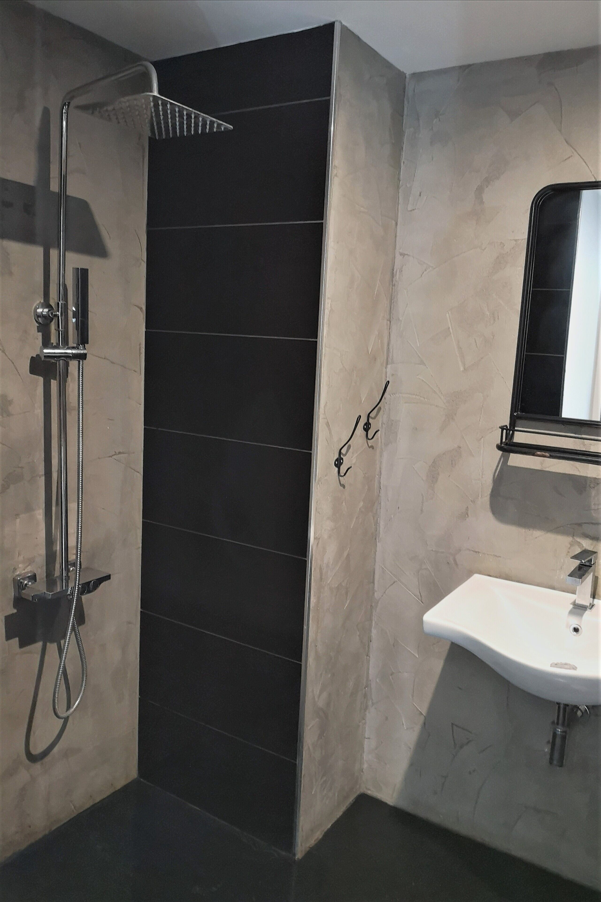 Un baño moderno con ducha a ras de suelo, un lavabo y un espejo.
