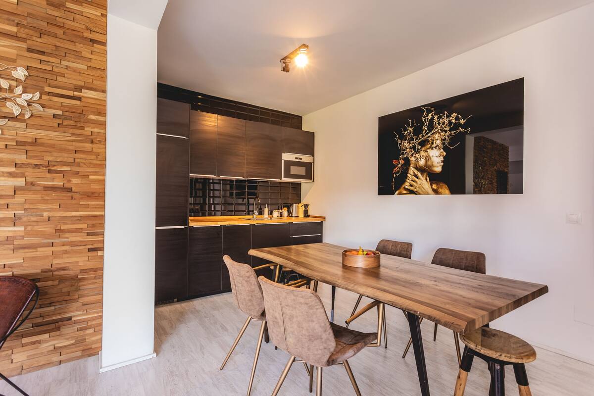 A modern kitchen with dark cabinetry, a wooden countertop, and a built-in oven.