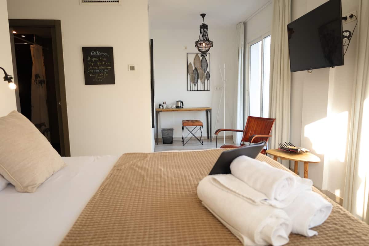 A hotel room with a bed, a desk, a chair, and a TV on the wall.