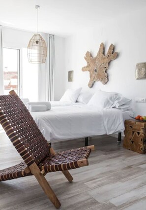 Ein modernes Schlafzimmer mit einem großen Bett, einem gewobenen Sessel und einem einzigartigen Wandkunstwerk.