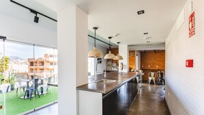 Eine moderne Küche mit einer langen Arbeitsplatte, hängenden Pendelleuchten und Blick auf den Außenbereich mit Sitzgelegenheiten.
