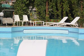 A swimming pool with white lounge chairs and a tiled edge. - Summa Resort (Roccasecca)