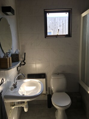 A bathroom with a white sink, a mirror, a window, and a toilet.