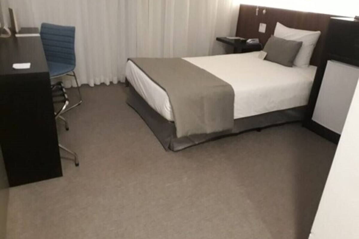 Una habitación de hotel con cama, escritorio, silla y mesita de noche.