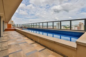 Une piscine sur le toit avec vue sur la ville, un sol carrelé et une rambarde.