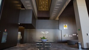 Un hall d’entrée moderne avec une table centrale, un espace salon et un plafond doté d’un éclairage encastré.