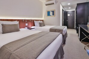Une chambre d’hôtel avec deux lits, un bureau et une armoire.