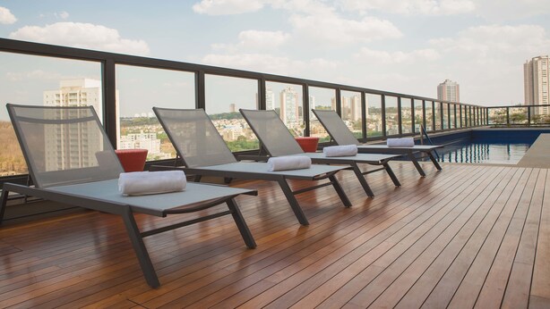 Un salon sur le toit avec des chaises longues, une piscine et une vue sur la ville.