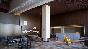 Un hall d’entrée moderne avec des espaces aménagés pour s’asseoir, un comptoir d’accueil et une grande plante en pot.