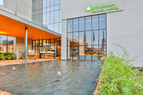 L’extérieur du Wyndham Garden Hotel présente une fontaine, une architecture moderne et une façade en verre.