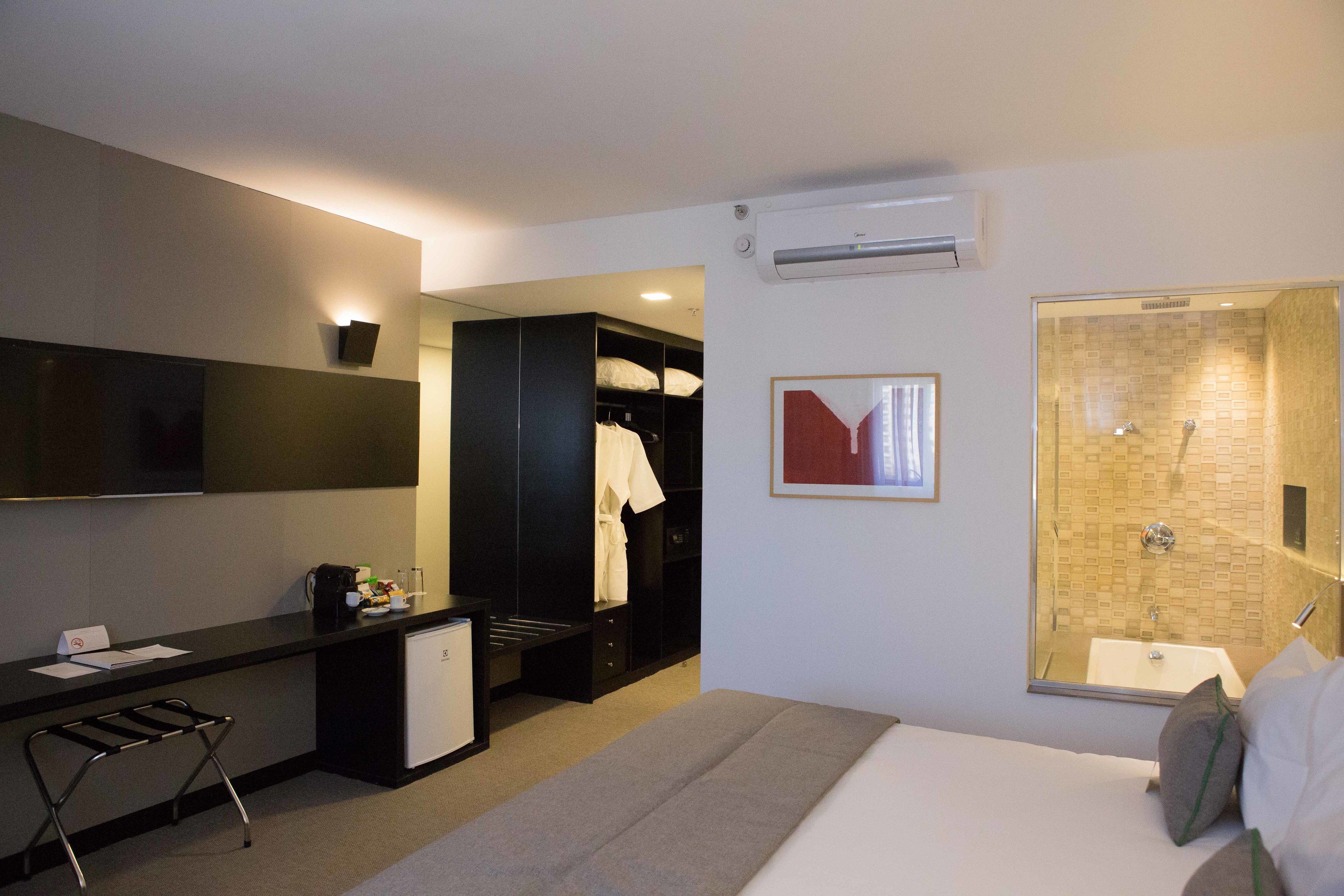 Une chambre d’hôtel comprenant un lit, un bureau, une chaise, une armoire et un espace douche.