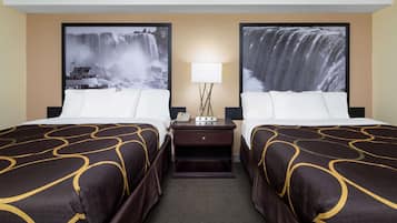 Quarto de hotel com duas camas, uma mesa de cabeceira com abajur e grandes quadros de cachoeira nas paredes.