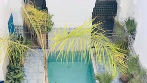 A small, enclosed pool area with tiled flooring and various potted plants. - Riad Ifoulki (Marrakech)