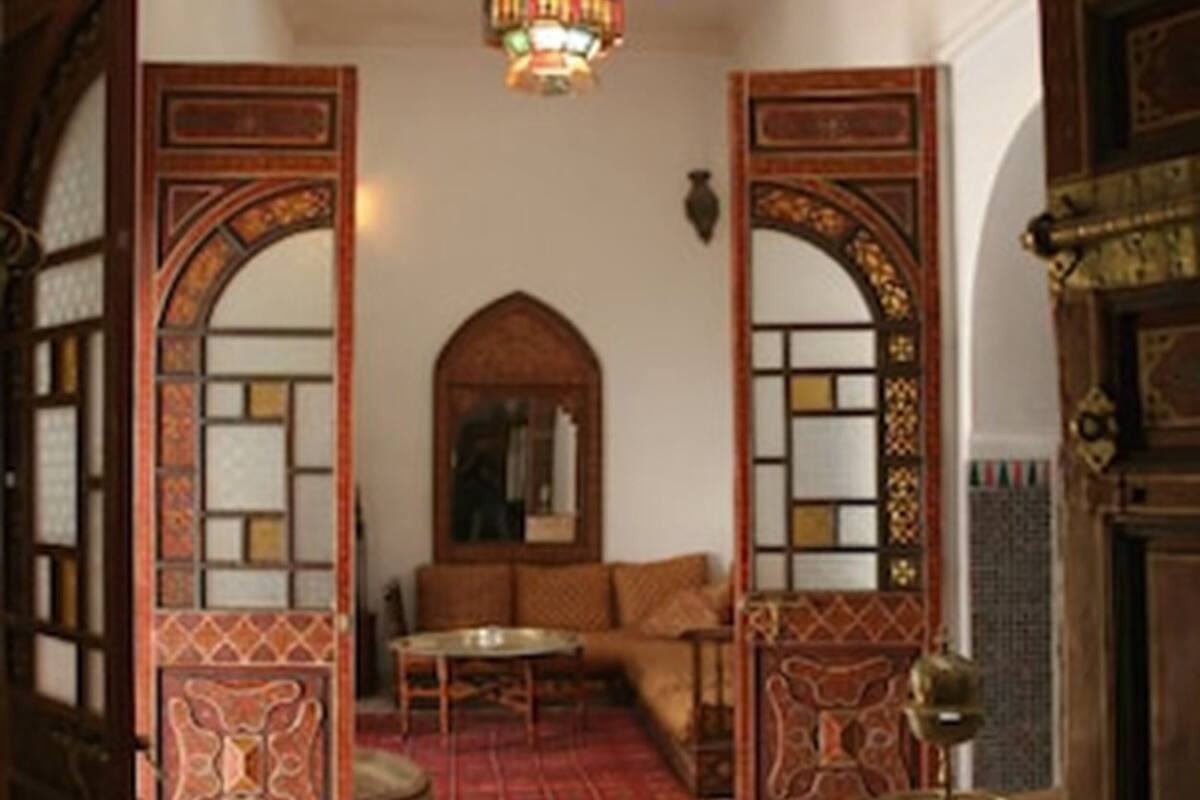 A traditional interior with a patterned floor, a central seating area, and ornate wooden doors.
